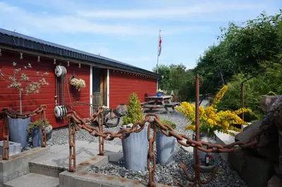 a fence with a chain in front of a building at Eget hus i sjøkanten ved fjorden in Langevåg