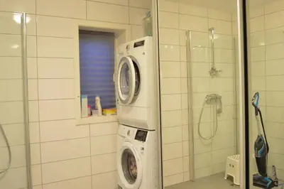 a washing machine in a bathroom with a shower at Modern 3-story house by the sea & public transport in Trondheim
