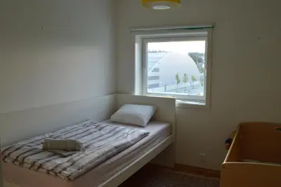 a small bed in a room with a window at Modern 3-story house by the sea & public transport in Trondheim