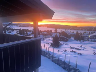 a sunset from the balcony of a house in the snow at Apartment Sjusjøen in Sjusjøen