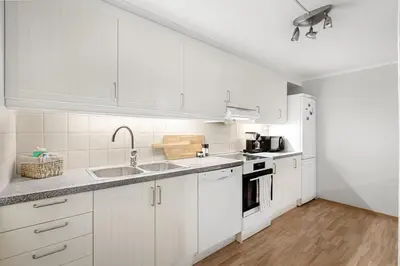 a white kitchen with white cabinets and a sink at Stilfull sentrumsnær leilighet in Bergen