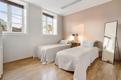 two beds in a white room with a mirror at Stilfull sentrumsnær leilighet in Bergen