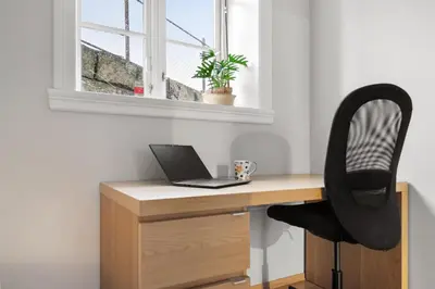a desk with a laptop and a chair next to a window at Stilfull sentrumsnær leilighet in Bergen