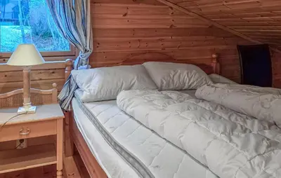 a bed in a log cabin with a table and a lamp at Beach Front Home In Omastrand in Gjuvsland
