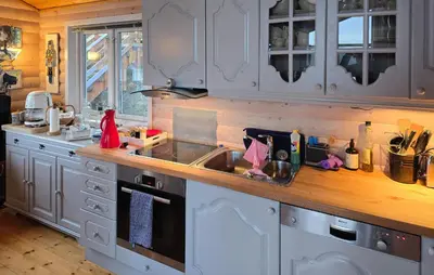 a kitchen with white cabinets and a sink at Beach Front Home In Omastrand in Gjuvsland