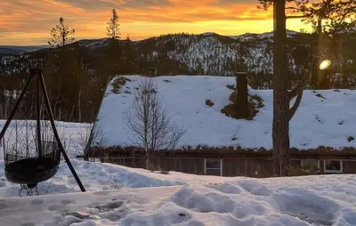 a snow covered roof of a house with the sunset in the background at Amazing Home In Eggedal With Sauna in Eggedal
