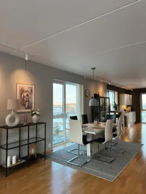 a dining room and living room with a table and chairs at Spacious apartment with a great view and parking in Trondheim