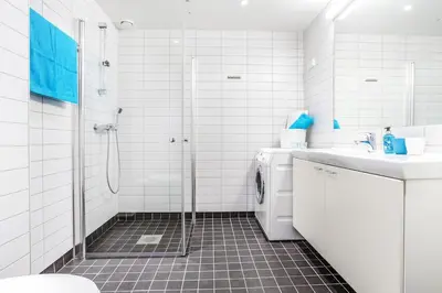 a white bathroom with a shower and a sink at Spacious apartment with a great view and parking in Trondheim