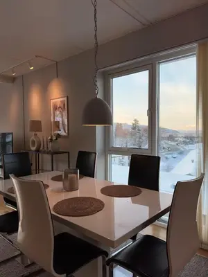 a dining room with a table and chairs and a large window at Spacious apartment with a great view and parking in Trondheim