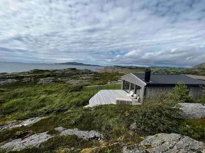 a small house sitting on top of a hill next to the water at Great cottage with unique views and high standard in Tørhogg