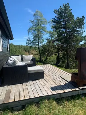a wooden deck with a couch on top of a house at Cabin at Kvamskogen with a great view in Kvam