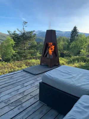 a bed and a fireplace on a wooden deck at Cabin at Kvamskogen with a great view in Kvam
