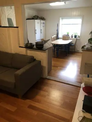 a living room with a couch and a kitchen with a table at Trondhjemsvegen in Gjøvik