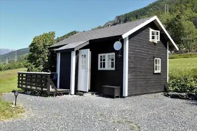 a small black house with a bench in front of it at Cabin 