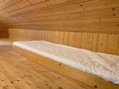a bed in a wooden room with a wooden floor at Cabin 