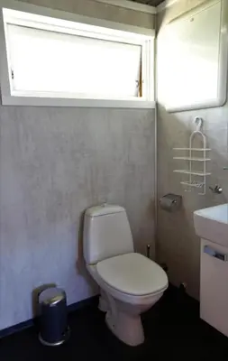 a bathroom with a white toilet and a window at Cabin 