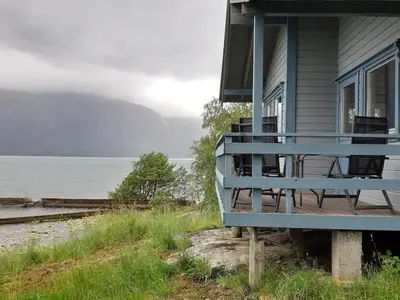 a house with a blue porch next to the water at Cabin 