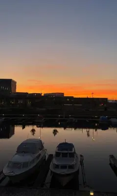 two boats are docked in a harbor at sunset at Apartment in city centre with view of the canal in Trondheim