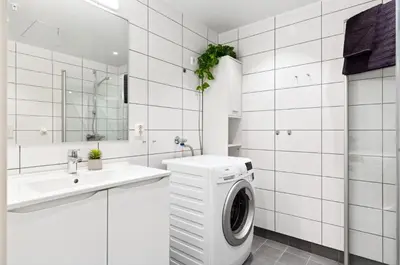 a white bathroom with a washing machine in a sink at Fin leilighet for VM in Trondheim