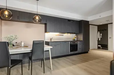 a kitchen with a white table and black cabinets at Fin leilighet for Ski VM in Trondheim