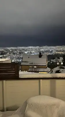 a snow covered balcony with a view of a city at Modern apartment with stunning view over city in Trondheim