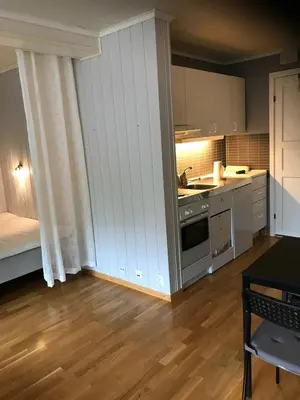a kitchen with white cabinets and a wooden floor at Bright and nice apartment in Trondheim
