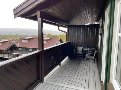 a balcony with a table and chairs on a house at Stylish 4-Bedroom Apartment With Mountain Views! in Beitostøl