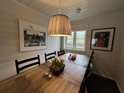 a dining room with a wooden table and a chandelier at Stylish 4-Bedroom Apartment With Mountain Views! in Beitostøl