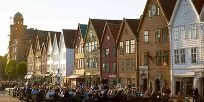 a crowd of people sitting on a street with buildings at Beautiful condo near Bryggen Balcony Fireplace in Bergen