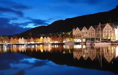 a group of houses on the water at night at Beautiful condo near Bryggen Balcony Fireplace in Bergen