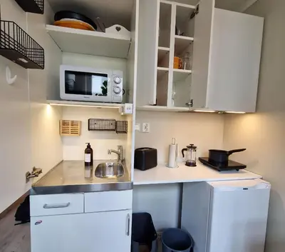 a small kitchen with white cabinets and a white refrigerator at Sleep well in Heart of Bergen - Beautiful street in Bergen