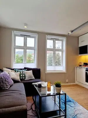 a living room with a couch and two windows at Sleep well in Cozy hideout - Bryggen across the bay in Bergen
