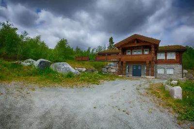 a log house with a gravel road in front of it at Spacious Cabin With Sauna & Scenic Terrace in Beitostøl