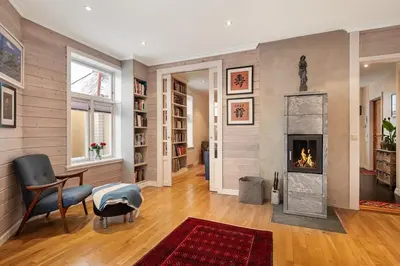 a living room with a fireplace and a chair at Cozy downtown apartment in Trondheim