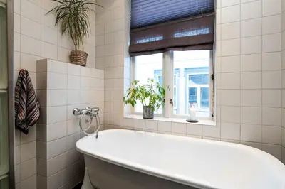 a white bathroom with a tub and a window at Cozy downtown apartment in Trondheim