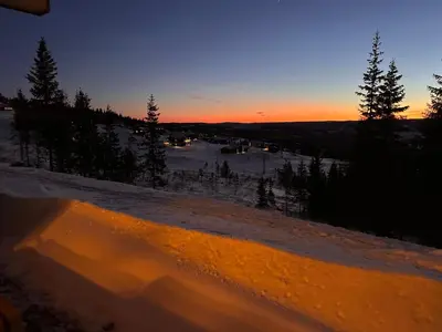 a snowboarder is riding down a hill at sunset at Hafjell Front 220B 8pers Ski InOut, Downhill bike in Hunder