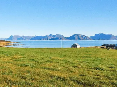 a field of grass with a view of the water and mountains at 6 person holiday home in Fjørtoft in Fjørtoft