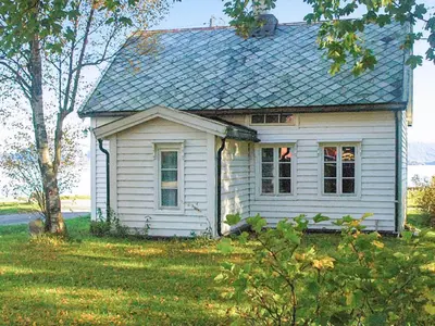 a small white house sitting in a field at 6 person holiday home in Fjørtoft in Fjørtoft