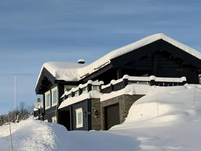 a house covered in snow with a pile of snow at Luxury And Comfort With Stunning Views in Beitostøl