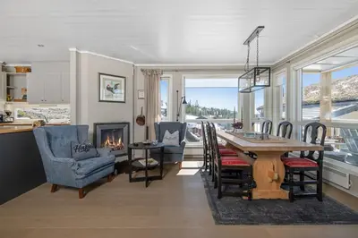 a dining room with a table and chairs and a fireplace at Utsiktsleilighet med ski in out på Hafjell 7 sengeplasser in Hunder