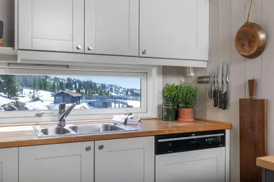 a kitchen with white cabinets and a sink and a window at Utsiktsleilighet med ski in out på Hafjell 7 sengeplasser in Hunder