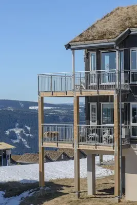 a building with a deck on top of a house at Utsiktsleilighet med ski in out på Hafjell 7 sengeplasser in Hunder