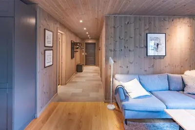 a living room with a blue couch and a hallway at Trysiltunet 6A in Trysil