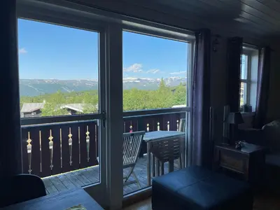 a room with a balcony with a view of the mountains at Family-Friendly Retreat With Fireplace And Balcony in Beitostøl