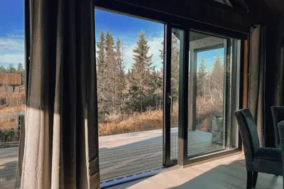 a room with a large window with a view of the woods at Modern Mountain Cabin - Outdoor Hot Tub - 8 Beds in Torpo