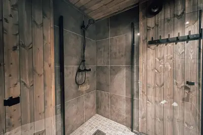 a bathroom with a shower with wooden walls at Modern Mountain Cabin - Outdoor Hot Tub - 8 Beds in Torpo