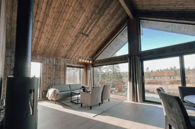 a living room with a couch and chairs and windows at Modern Mountain Cabin - Outdoor Hot Tub - 8 Beds in Torpo