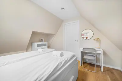 a white bedroom with a bed and a chair at Marken Townhouse NEW 2025 in Bergen