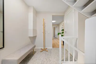 a hallway with white walls and a staircase with a bench at Marken Townhouse NEW 2025 in Bergen