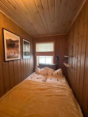 a bedroom with a bed in a wooden room at Cabin at Furutangen - 3 bedroom family cabin in Åmot